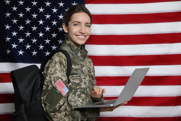 Female cadet with backpack and laptop against American flag. Military education - Фото, зображення