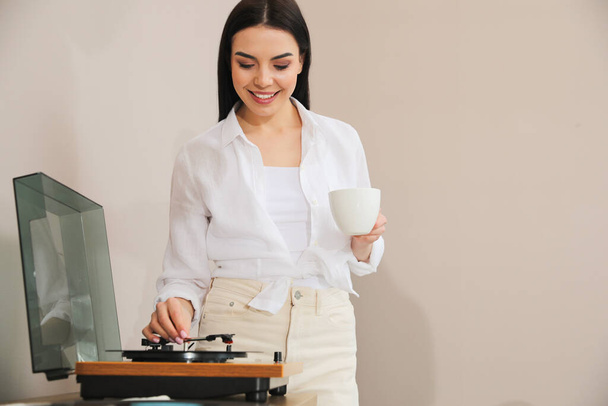 Woman using turntable on beige background. Space for text - Фото, зображення