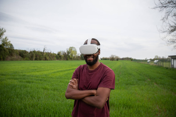 um menino africano brinca com seus fones de ouvido de realidade virtual em um campo - Foto, Imagem
