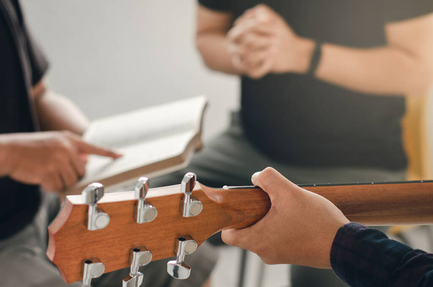 Молоді чоловіки грають на гітарі, хвалять бога музикою і поклоняються богу в християнській сім'ї. Дружба - християнське поняття.. - Фото, зображення