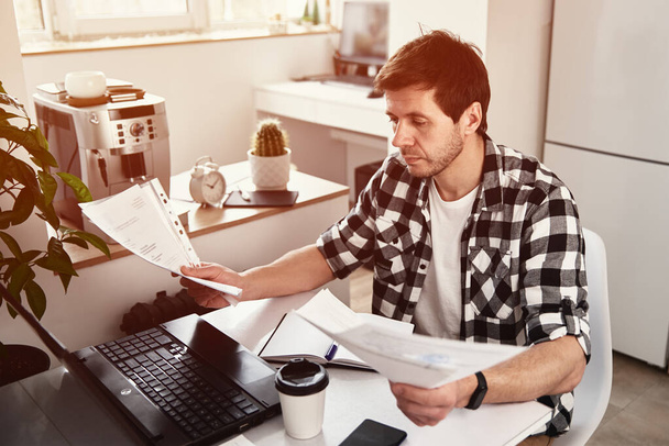 Homem trabalha em casa escritório com laptop e documentos - Foto, Imagem