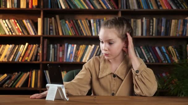 Iloinen koulutyttö takki puhuu ystäville älypuhelimen kautta - Materiaali, video
