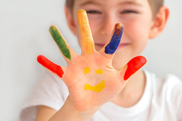 Portrait of joyful cute preschooler little boy 5-6 years with colorful painted hands. Smiley hands. Finger drawing, education and child development. Happy childhood. - Foto, Imagen