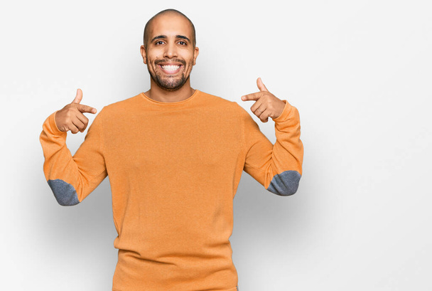 Взрослый латиноамериканец в обычном зимнем свитере выглядит уверенно с улыбкой на лице, указывая на себя пальцами гордым и счастливым.  - Фото, изображение