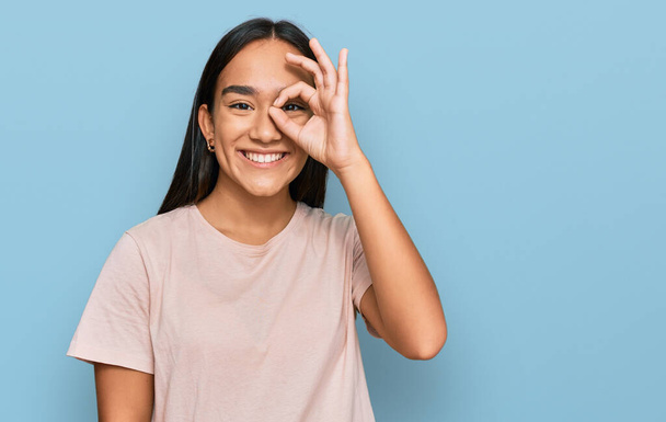 joven asiático mujer usando casual ropa haciendo ok gesto con mano sonriendo ojo mirando a través de dedos con feliz cara.  - Foto, Imagen