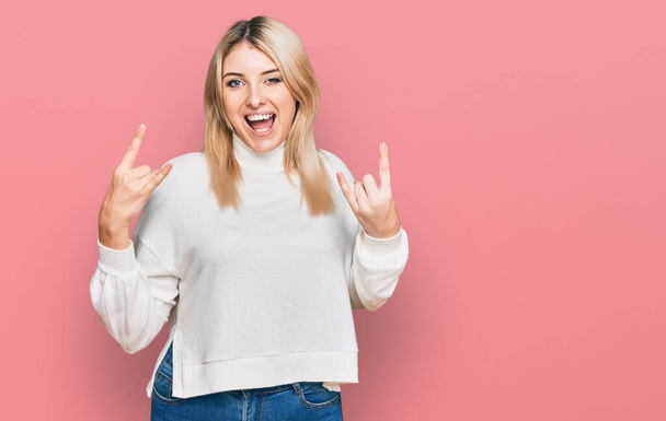 Young caucasian woman wearing casual winter sweater shouting with crazy expression doing rock symbol with hands up. music star. heavy music concept.  - Photo, Image
