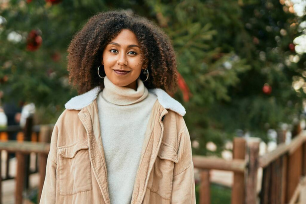 Молода афроамериканська жінка, яка посміхається, радісно стоїть біля парку.. - Фото, зображення