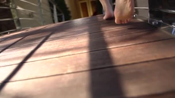 Femme pieds nus court le long d'une terrasse en bois dans un peignoir flottant  - Séquence, vidéo