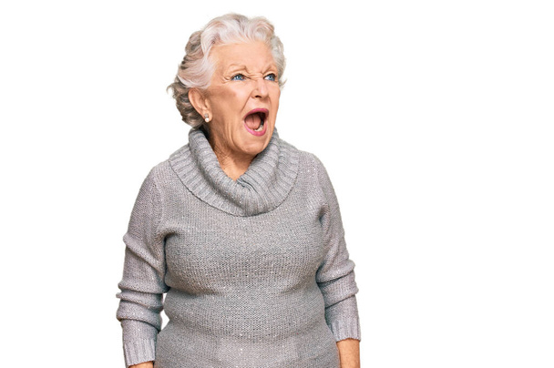 Senior mulher de cabelos grisalhos vestindo camisola de inverno casual irritado e louco gritando frustrado e furioso, gritando com raiva. raiva e conceito agressivo.  - Foto, Imagem