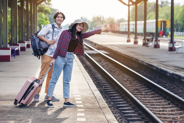 man & woman with backpack waiting for train at railway station. loving couple traveler travel together on holiday - Photo, Image
