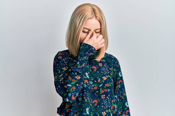 Young blonde woman wearing casual clothes tired rubbing nose and eyes feeling fatigue and headache. stress and frustration concept.  - Fotoğraf, Görsel
