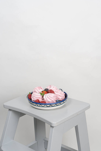 Egy tányér házi mályvacukorral, bogyókkal díszítve. Szürke háttérrel. Péksütemény reklám koncepció, főzés titkok - Fotó, kép