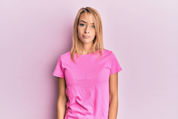 Beautiful blonde woman wearing casual pink tshirt looking sleepy and tired, exhausted for fatigue and hangover, lazy eyes in the morning.  - Фото, зображення
