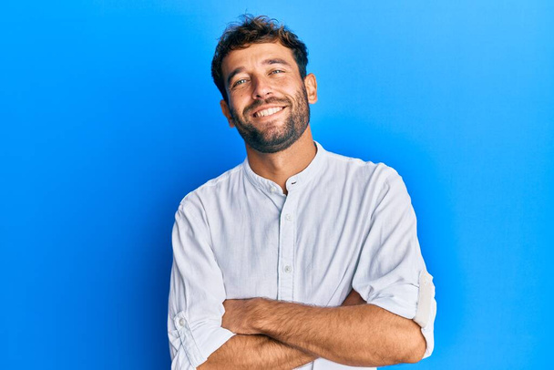 Hezký muž s vousy v elegantní košili šťastný obličej s úsměvem se zkříženýma rukama dívá do kamery. pozitivní osoba.  - Fotografie, Obrázek