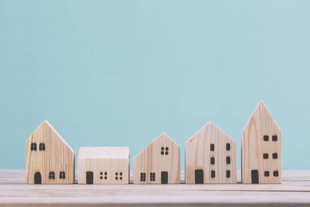 Построение различных моделей деревянных домов на синем фоне, управление концепцией инвестиций в недвижимость - Фото, изображение