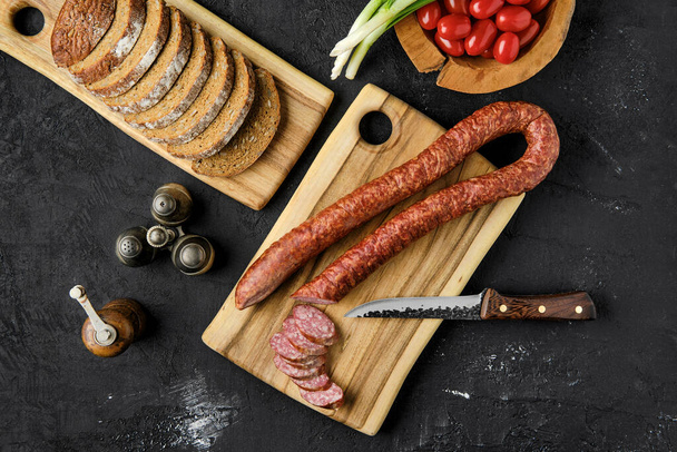 Overhead view of smoked pork sausage rings on wooden cutting board on kitchen table  - Φωτογραφία, εικόνα