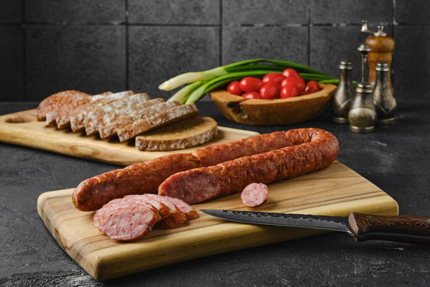 Smoked lamb sausage rings on wooden cutting board on kitchen table  - Φωτογραφία, εικόνα