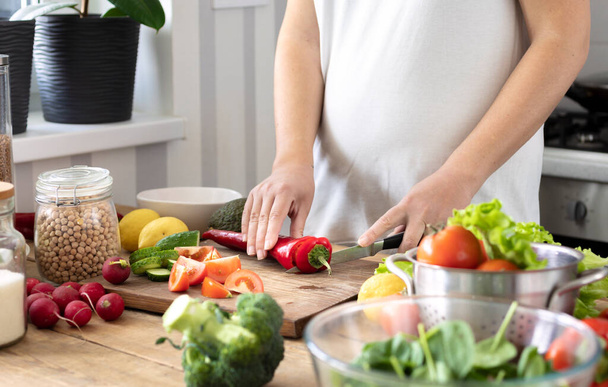 Healthy lifestyle and wholesome food concept. Pregnant women in early pregnancy preparing a healthy breakfast or dinner from fresh vegetables in the home kitchen - Fotoğraf, Görsel