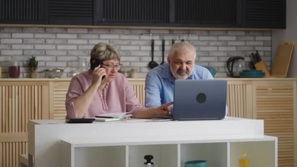 důchodci se radí s pojišťovnou a finančním poradcem telefonicky sedí doma v kuchyni, střední portrét manželského páru ve věku doma - Záběry, video