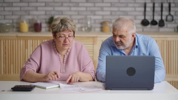 anziani coppia sposata sta calcolando le bollette di utilità seduti insieme in cucina in casa, ritratto medio - Filmati, video