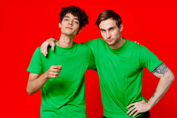 Two man green t-shirts embrace emotions friendship red background - Photo, Image