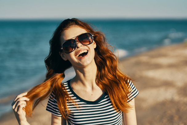 heureuse femme aux cheveux roux en lunettes de soleil au bord de la mer émotions amusantes - Photo, image