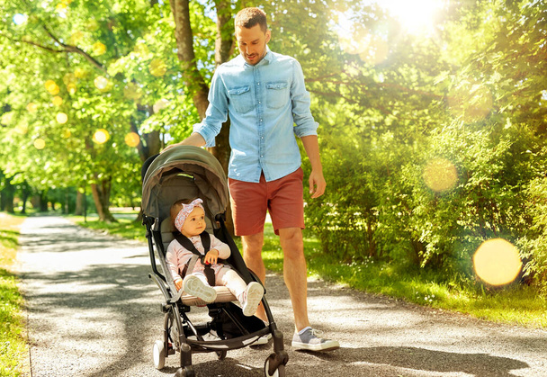 happy father with child in stroller at summer park - Foto, imagen