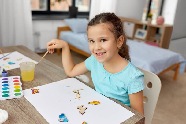 little girl painting wooden items at home - Foto, Imagen