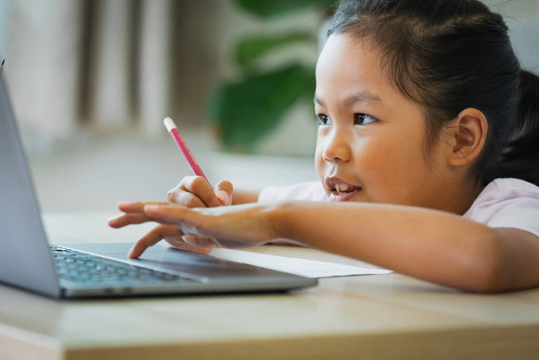 Aasian lapsi tyttö opiskelija opiskella verkossa opettajan kanssa videopuhelu. Lapsi on kotiopetuksessa kannettavan tietokoneen kanssa karanteenin aikana Covid 19 pandemian vuoksi. - Valokuva, kuva