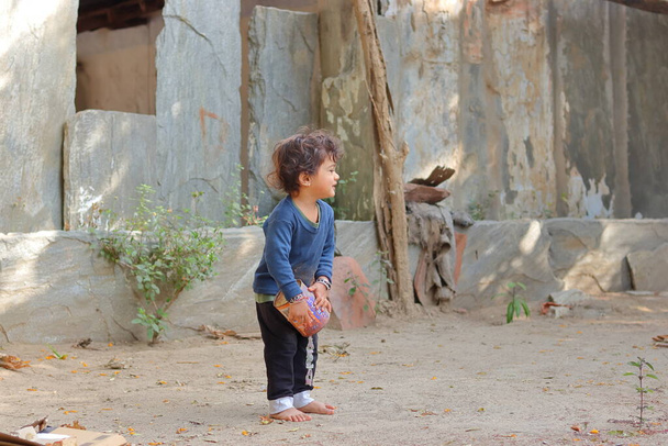 .Retrato de primer plano de un niño pequeño asiático jugando con arena y latas en el patio de la casa.Concepto de la infancia, hermoso niño indio jugando, recuerdos de la infancia. - Foto, Imagen