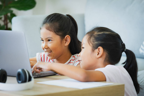 Dvě asijské dítě dívka studenti studovat online s učitelem videohovory dohromady. Sourozenci se během karantény učí s notebookem kvůli pandemii Covid 19. - Fotografie, Obrázek