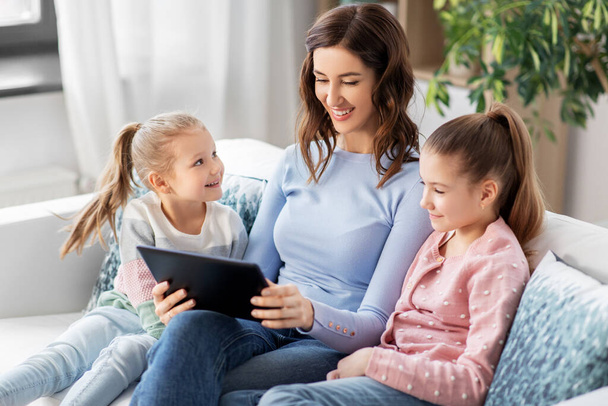 happy mother and daughters with tablet pc at home - Zdjęcie, obraz