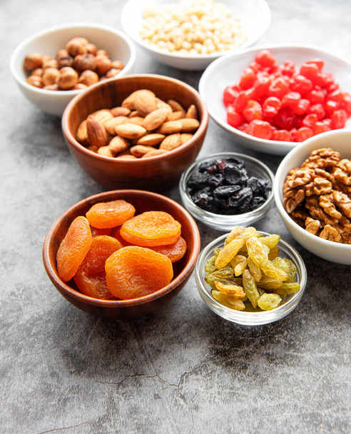 Bowls with various dried fruits and nuts on a gray concrete background - Foto, Imagem