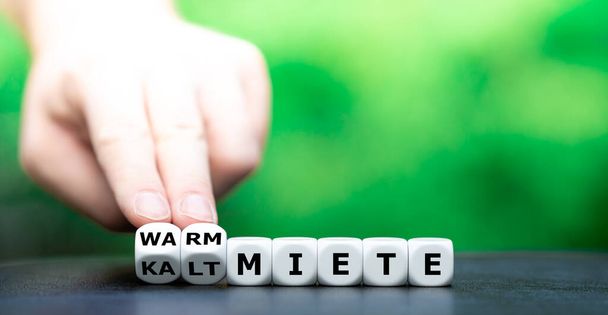 Hand turns dice and changes the German expression "kaltmiete" (rent without additional costs) to "warmmiete" (rent including additional costs). - Photo, Image