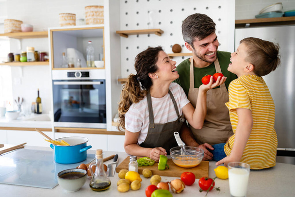 Happy young family preparing healthy food together in kitchen - Zdjęcie, obraz