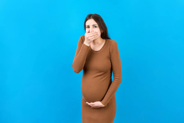Вагітна жінка страждає від токсикозу. Токсикоз вагітності. Вагітна леді відчуває себе хворим Nausea стоїть на кольоровому ізольованому тлі. Вільний простір
. - Фото, зображення
