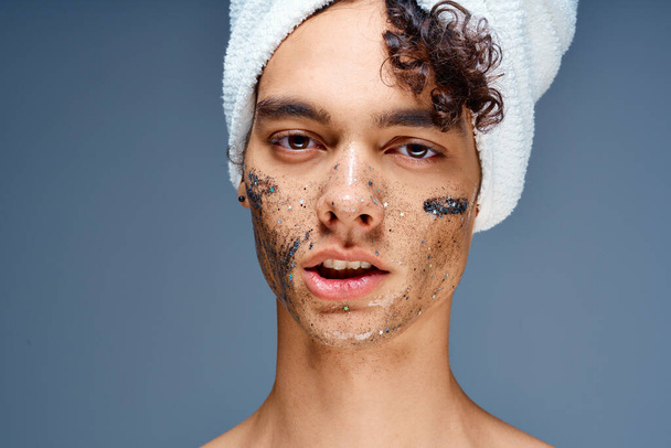 lindo chico con una toalla en la cabeza crema facial cuidado de la piel - Foto, imagen