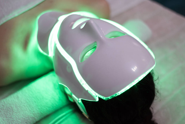 Žena s LED světelné terapie obličeje a krku kosmetické masky fotonová terapie. Domácí péče o pleť a můj časový koncept - Fotografie, Obrázek