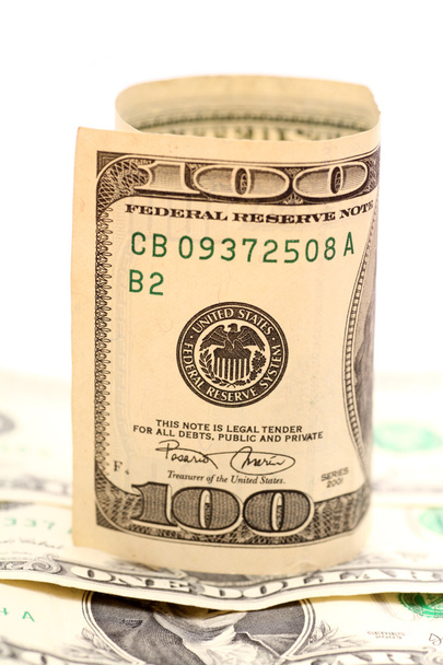 Rotolo di cento dollari Bill su un mucchio di banconote dollaro contro sfondo bianco. Primo piano
. - Foto, immagini
