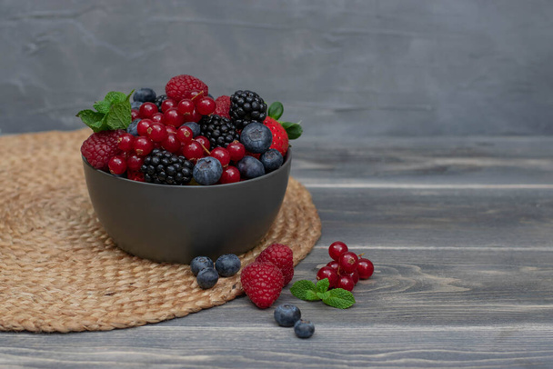 Ripe sweet different berries in bowl on wooden table. Harvest Concept. Fresh berries. - Фото, изображение