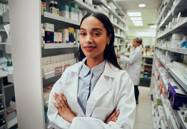 Young pharmacist with crossed arms looking at camera in drugstore - Foto, afbeelding