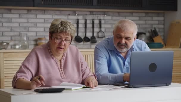 starší manželé tráví víkend doma, žena počítá účty za služby a její manžel surfuje na internetu - Záběry, video