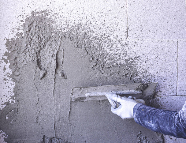 Bauarbeiter verputzen die Fassade des Hauses. Arbeiter Putzwerkzeug Gips Marmor auf Innenputz rauh - Foto, Bild