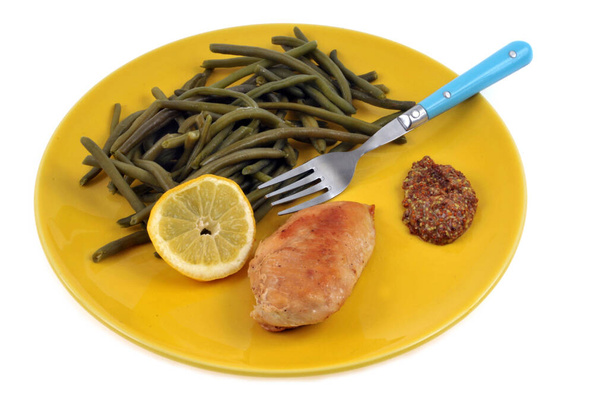 Assiette avec du blanc de poulet et des haricots verts et une rondelle de citron en gros plan sur fond blanc - Foto, imagen