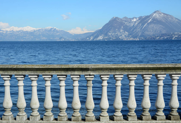 Terassi, jossa on kaide Maggiore-järven sinisillä vesillä Stresassa Alppien ollessa taustalla. - Valokuva, kuva