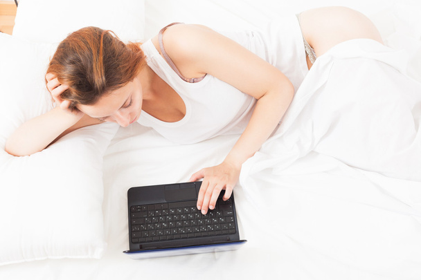 Woman awake with laptop on her bed - Zdjęcie, obraz