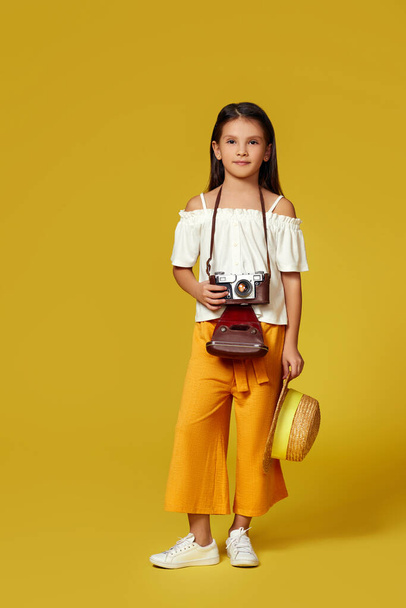 cute little girl with retro camera on yellow background. - Fotó, kép