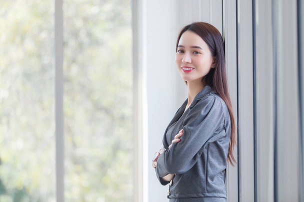 Portrait Asian business woman who has long hair stands and arm crossed in workplace. - 写真・画像