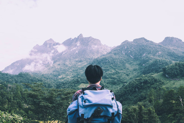 スコットランドのシャツと雲の上の山のピークで黒い帽子のハイキングでアジアの若い男と霧ハイカー屋外。土井ルアンチェンマイ｜ダオ・チェンマイ県. - 写真・画像