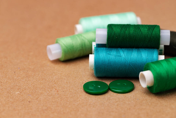 Thread spools and buttons on beige background - Photo, Image